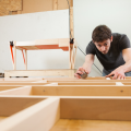 Samuel Hélias penché sur une réalisation en bois dans son atelier.